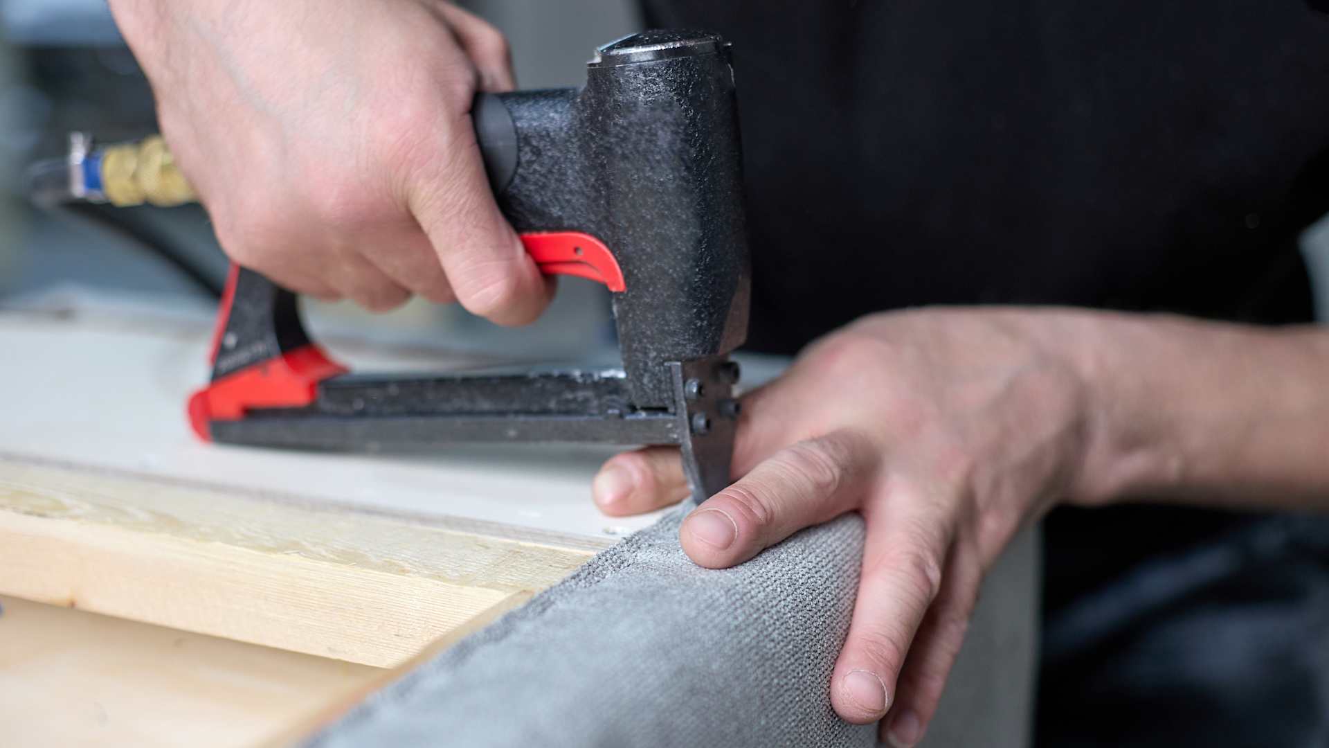 Man with staple gun reupholstering couch